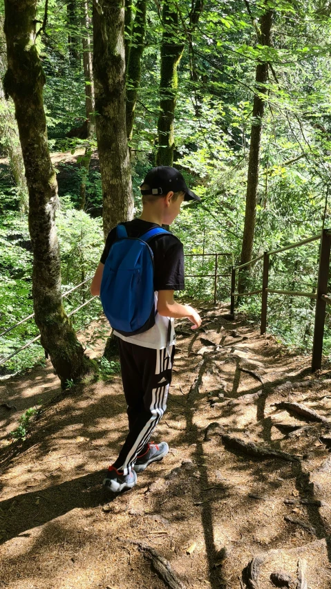 boy in blue backpack standing by tree