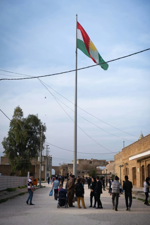 people are walking on the pavement in front of the flagpole