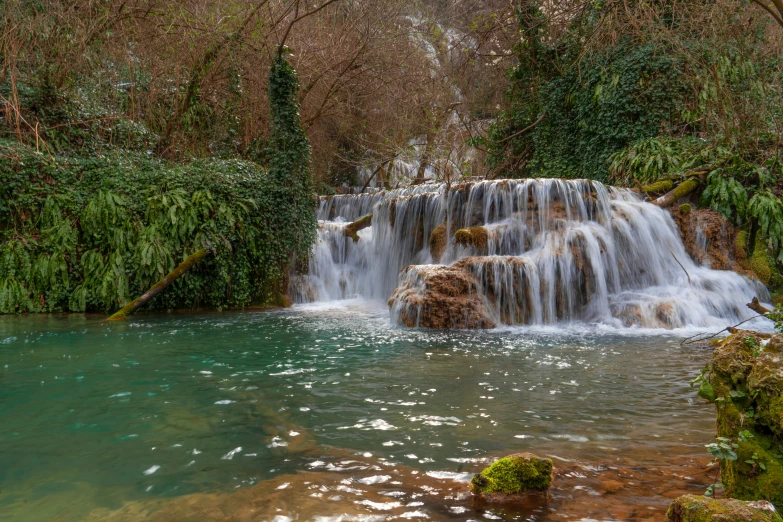 a waterfall cascade falling down into a green pool