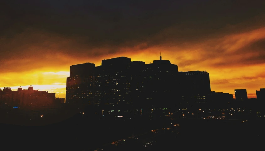 a city skyline with dark clouds and yellow buildings