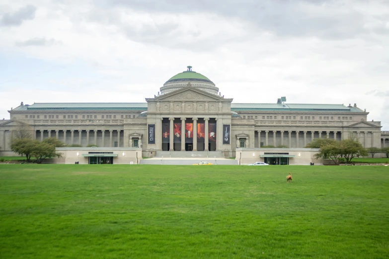 two benches sitting in the grass in front of a large building