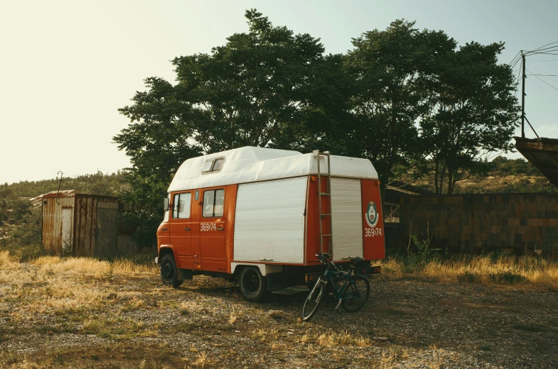 an old bus is parked near a tree and a fence