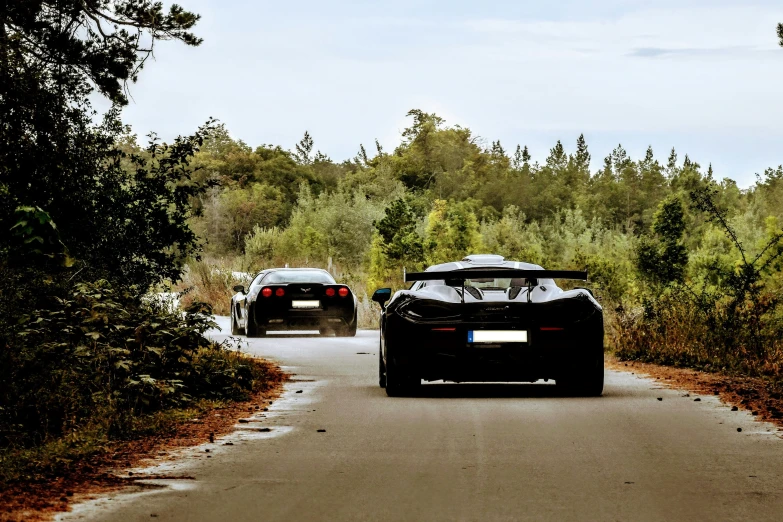 two cars parked on the side of a road near trees