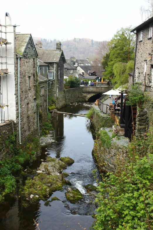 a small stream is running alongside some old buildings