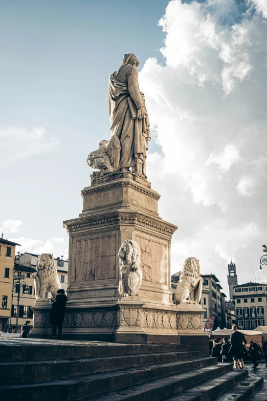 people are walking around an ornate marble fountain in a city