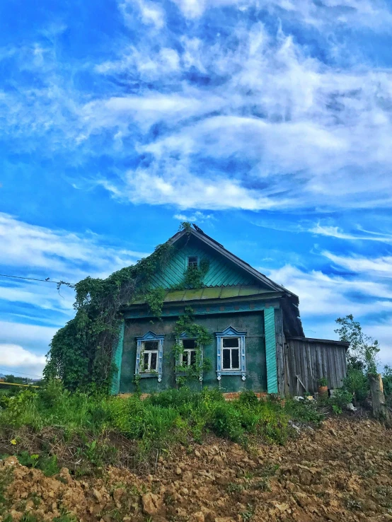 a green house sitting on the side of a dirt hill