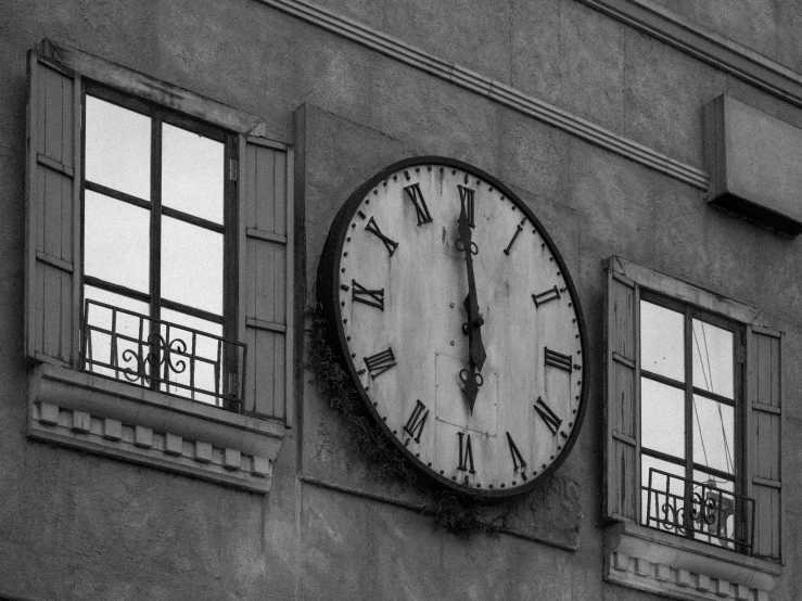 a clock on the outside wall of a building with windows