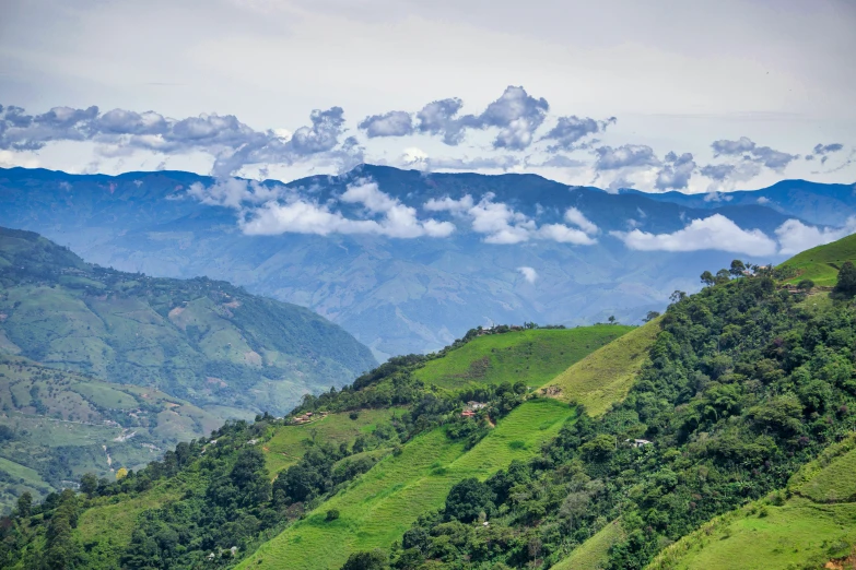 the mountains have clouds moving over them and grass on each side