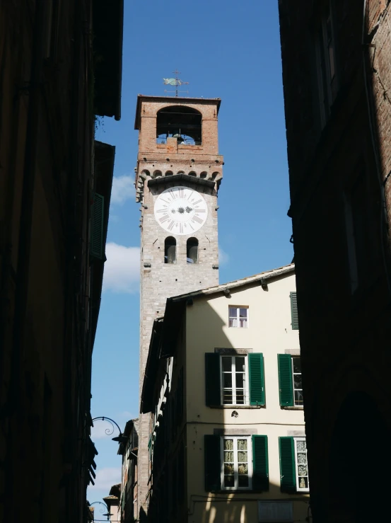 the large brick clock tower stands tall above the small buildings
