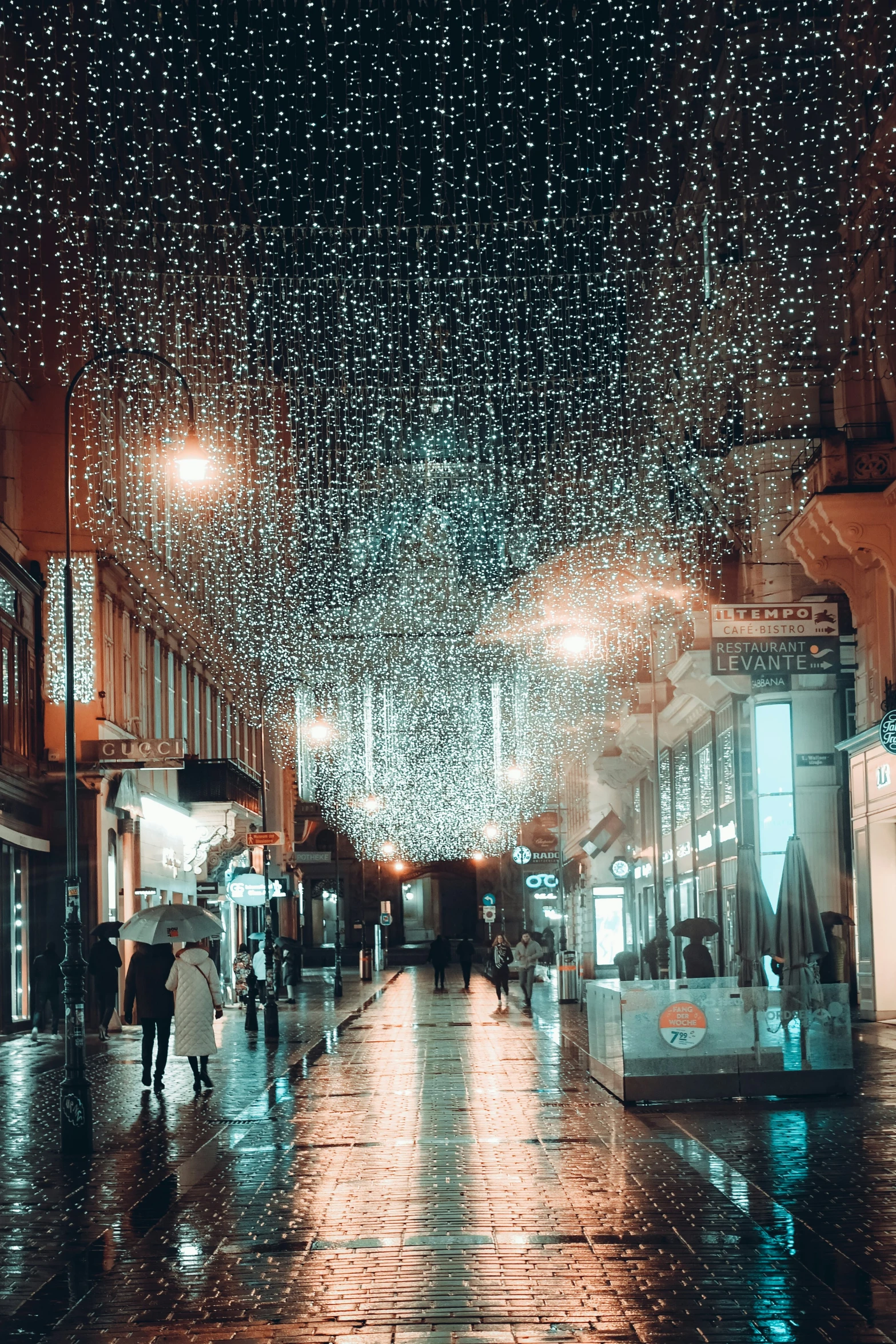 people on a rainy street in the rain under a lot of lights