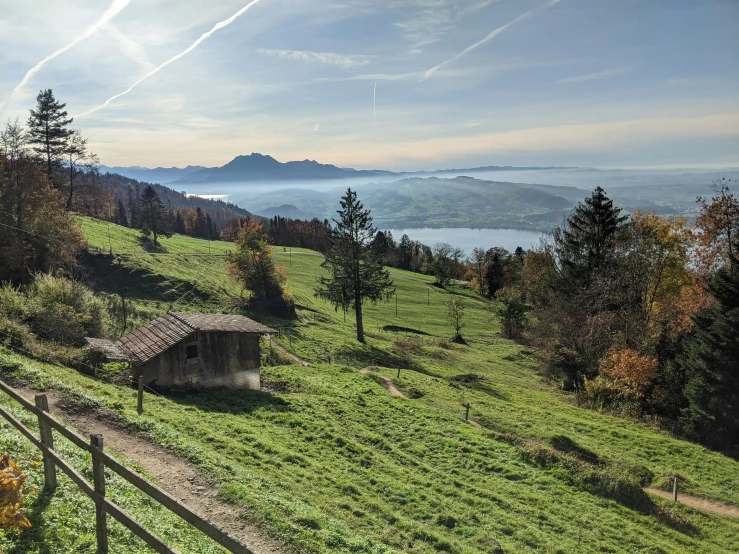 a hut on a grassy hillside with water in the distance