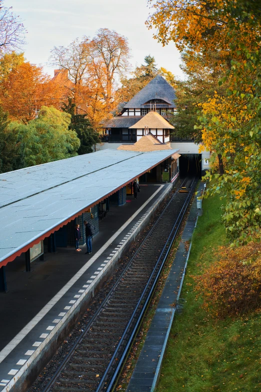 a train station with a walkway and tree lined path in front