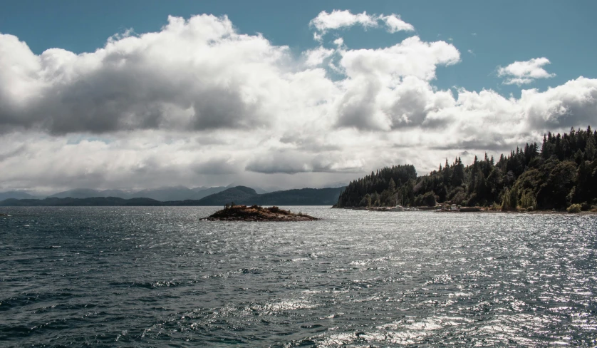 some clouds are hovering over the water and hills