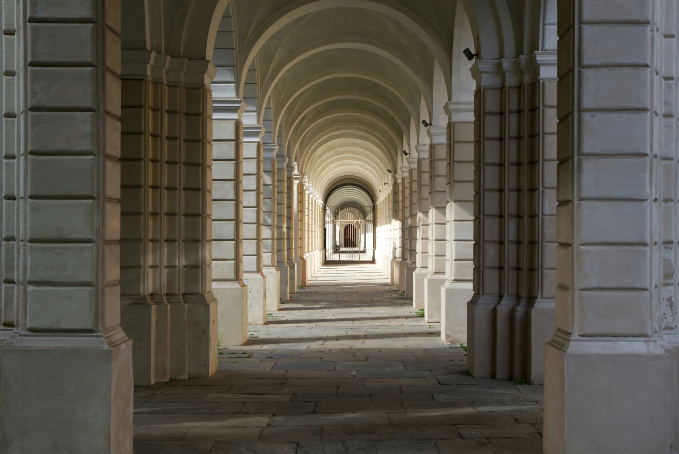 an arch - lined hallway leading to an outside courtyard