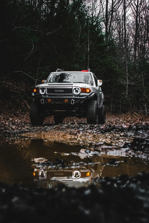 a truck parked near some water in the forest