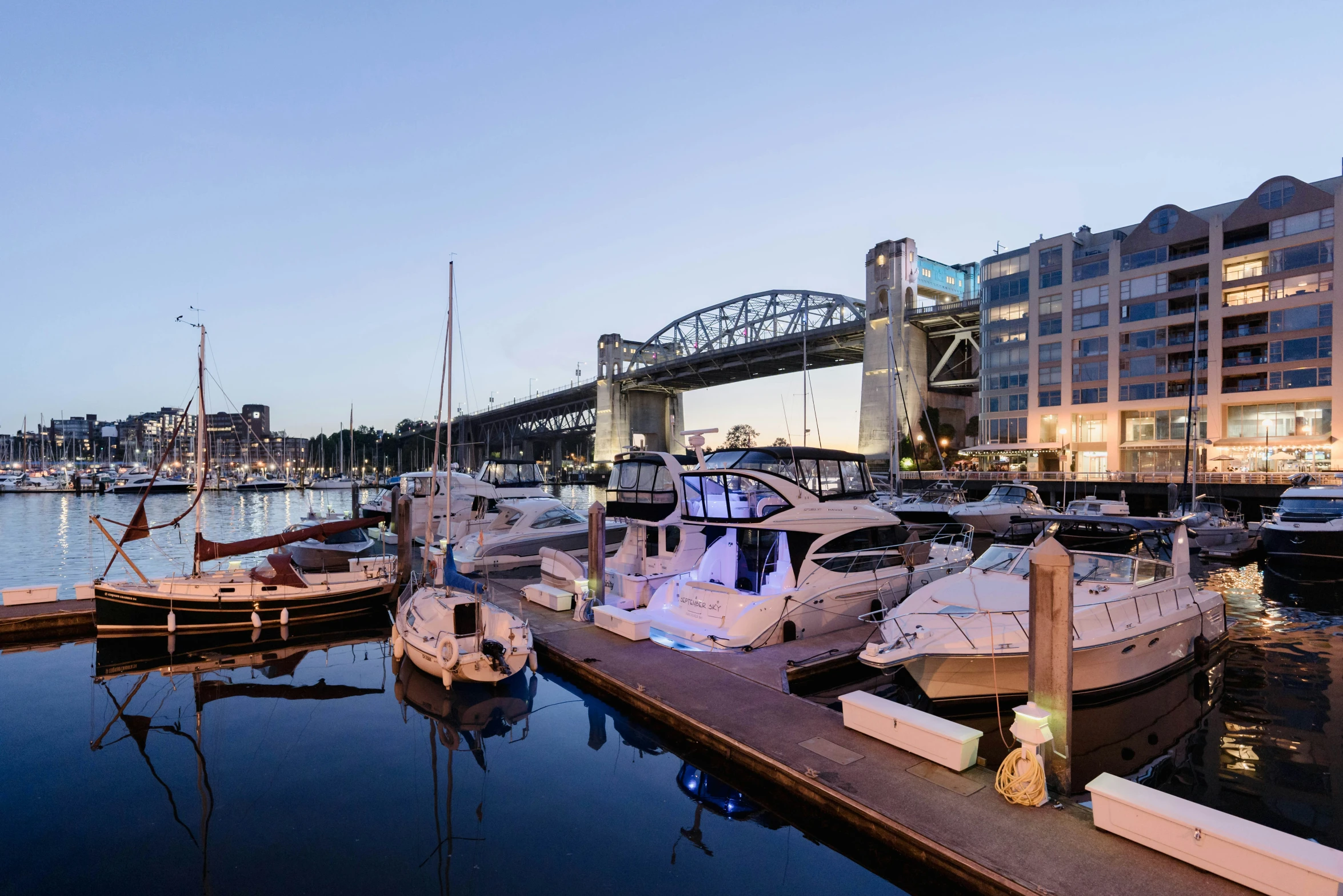 boats are docked in the water near a large bridge