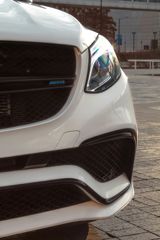 the front end of a white car parked on brick pavement