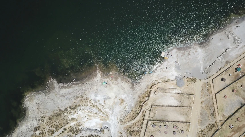 people stand on the beach near a body of water