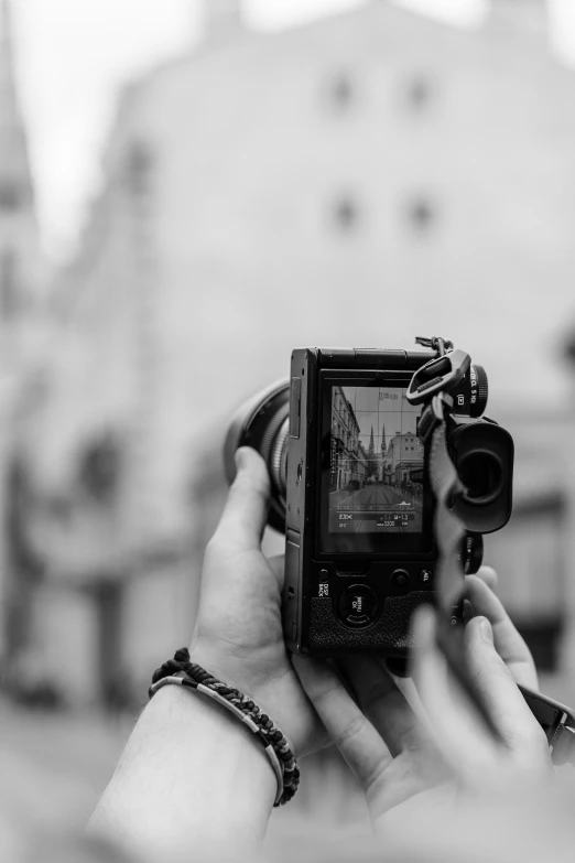 a person holding up a small camera in front of a building
