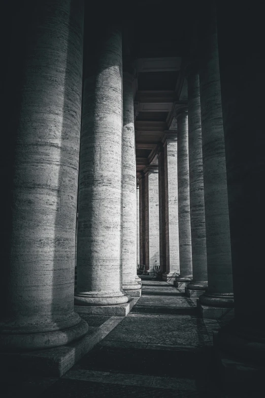 rows of large pillars sitting along a wall with water underneath