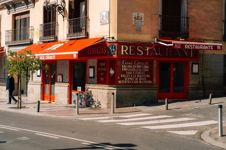 a restaurant on a corner with two people walking by