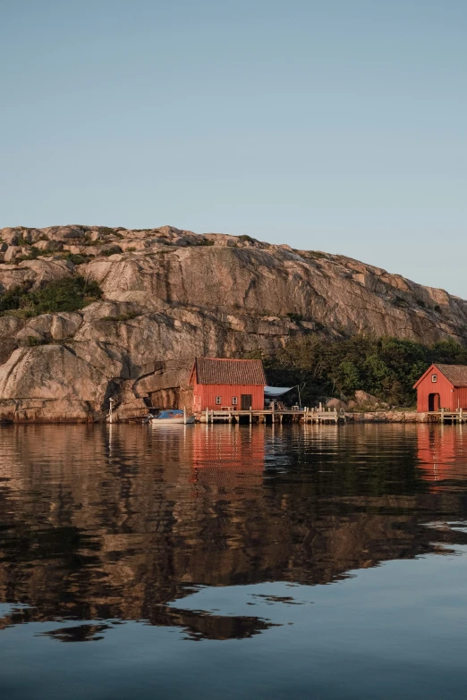 two red house's floating on water near rocky shoreline