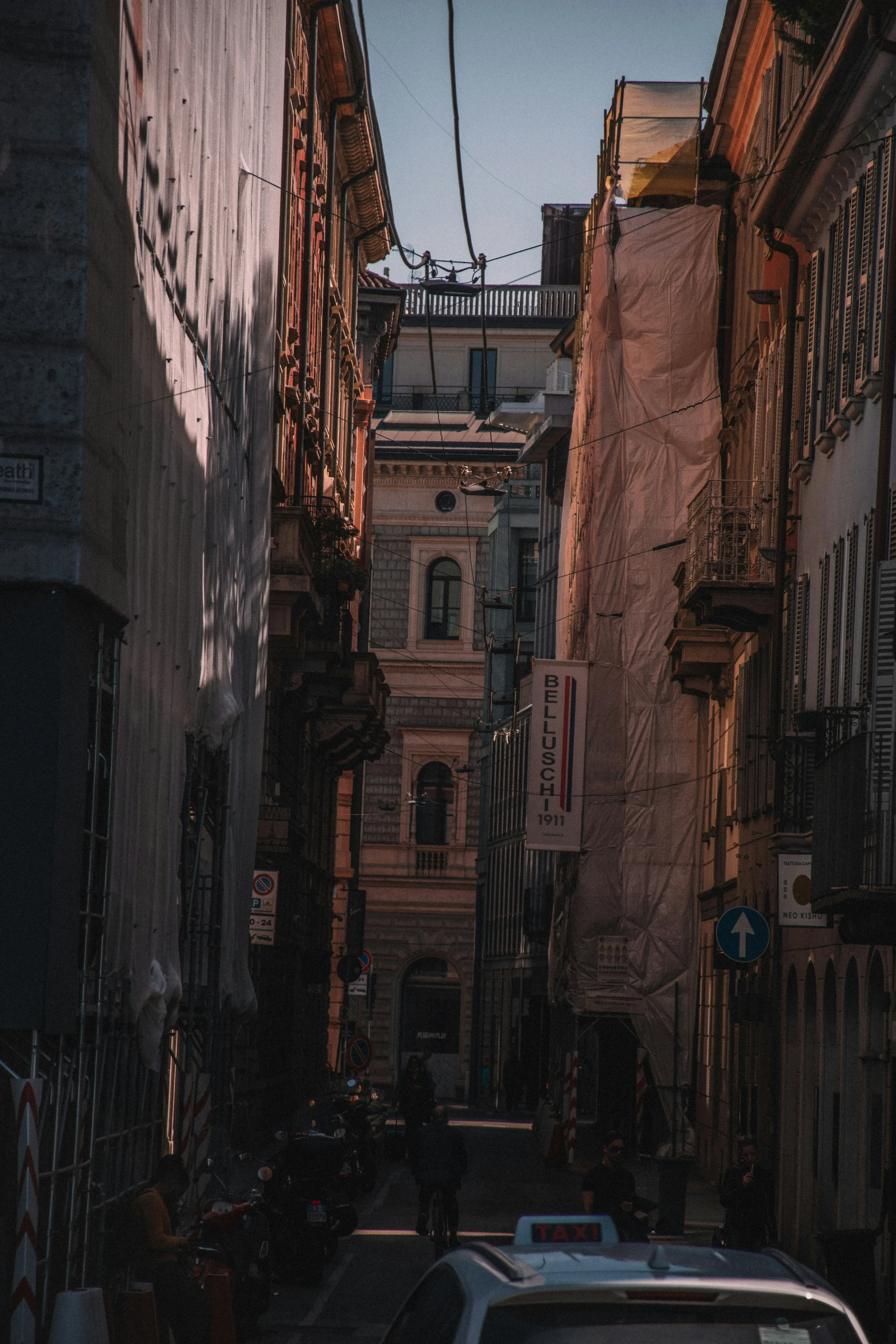 a small white car driving down an alley