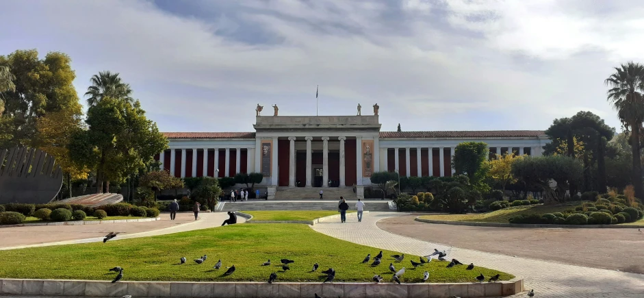 a large building with many pigeons standing in front of it