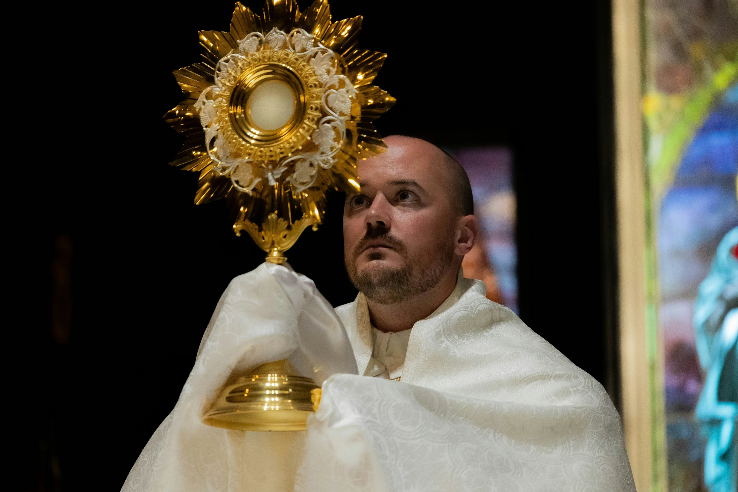 a man holding a large bell with the cross