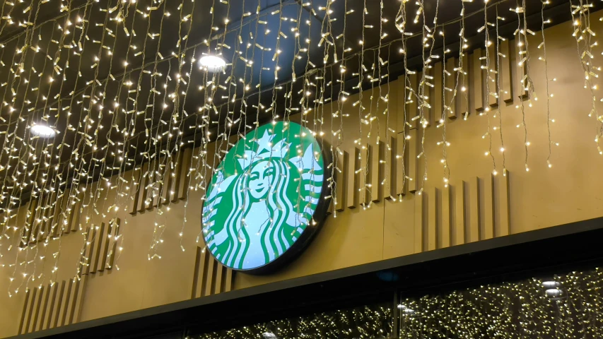 a starbucks sign with light strings hanging from the outside