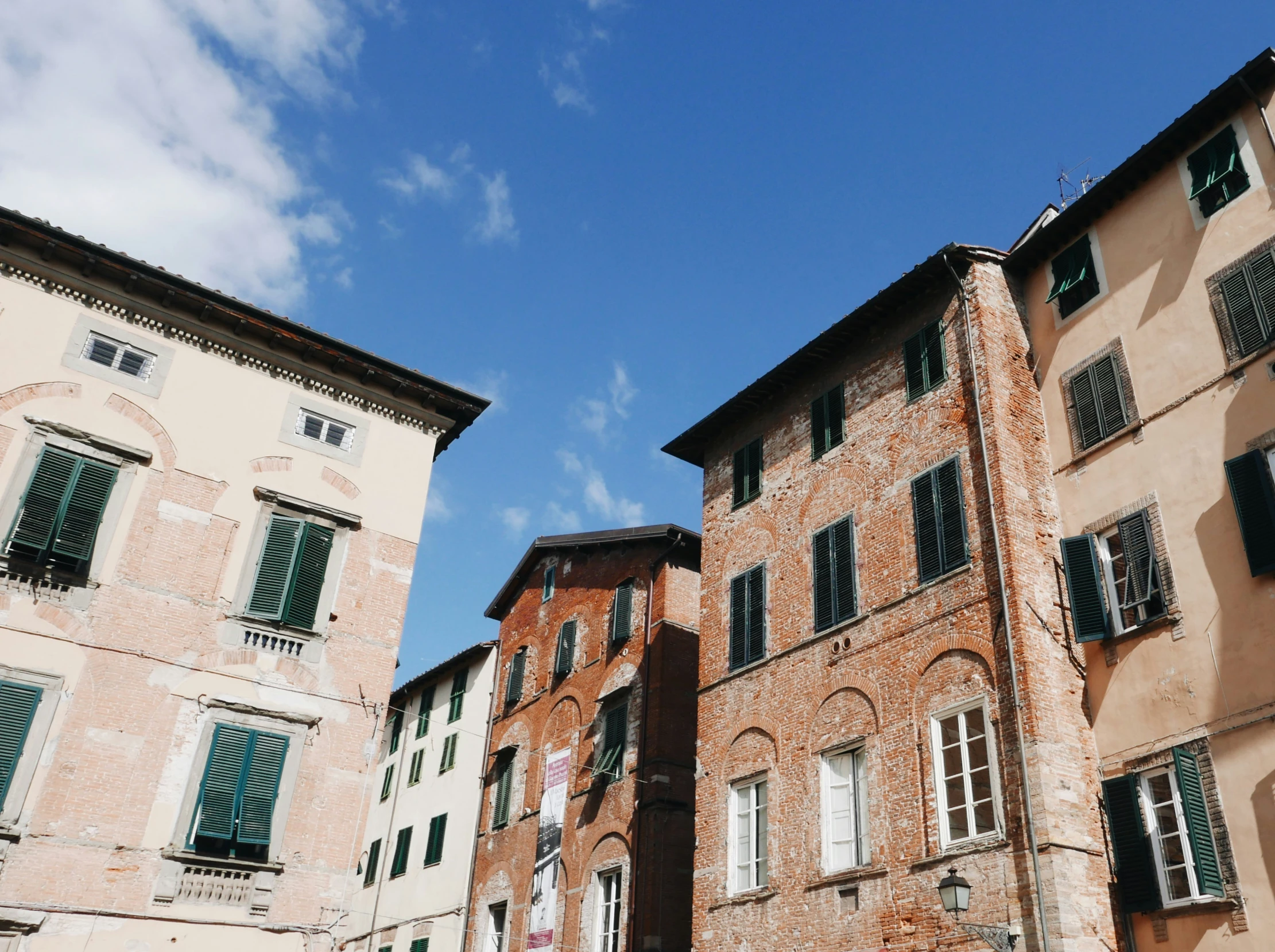 several buildings with green shutters and a clock on each window