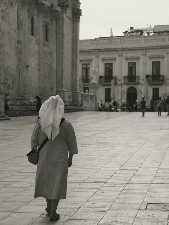 an older woman in nun garb is walking down the street