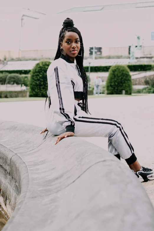 a woman poses in an outdoor environment on top of a stone wall