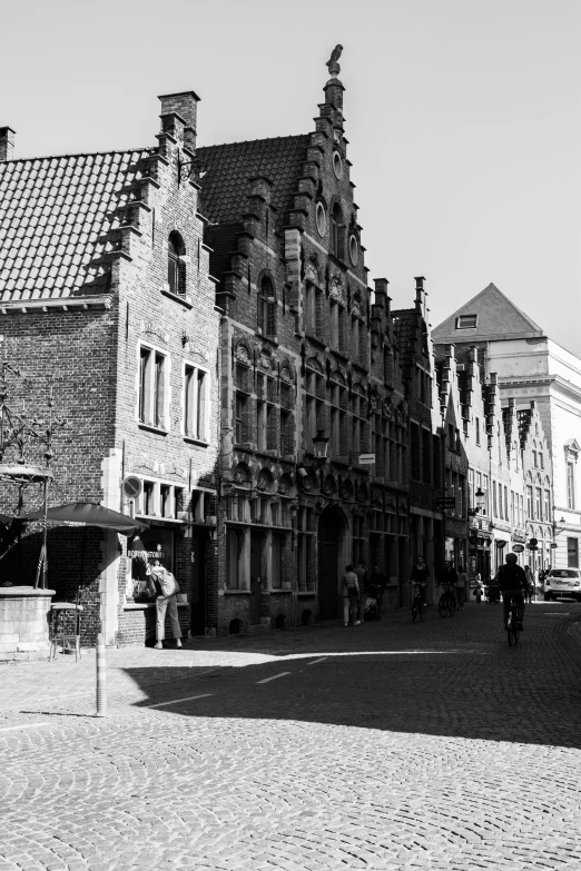 a couple of people walk along the side walk of buildings