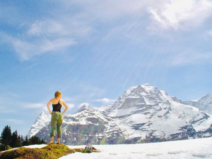 a woman standing on top of a hill overlooking the mountains