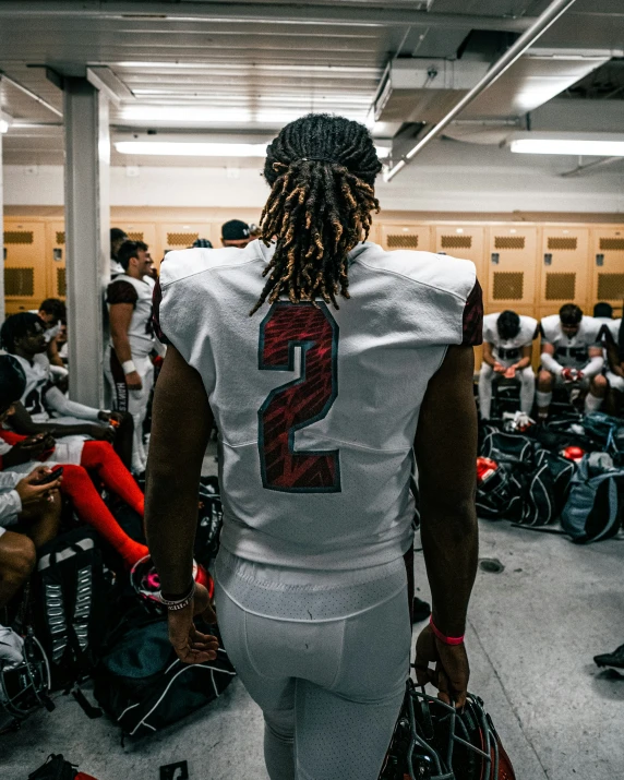 a football player with dreadlocks walking into the locker room