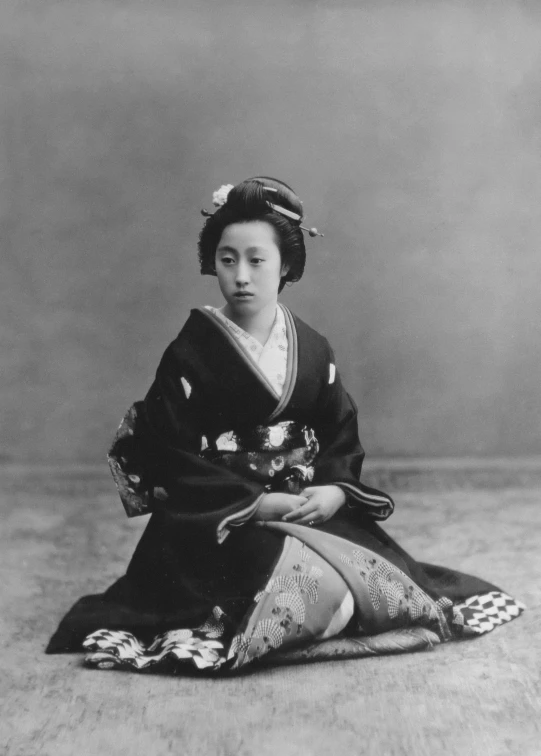 a japanese lady in traditional garb sits on a floor