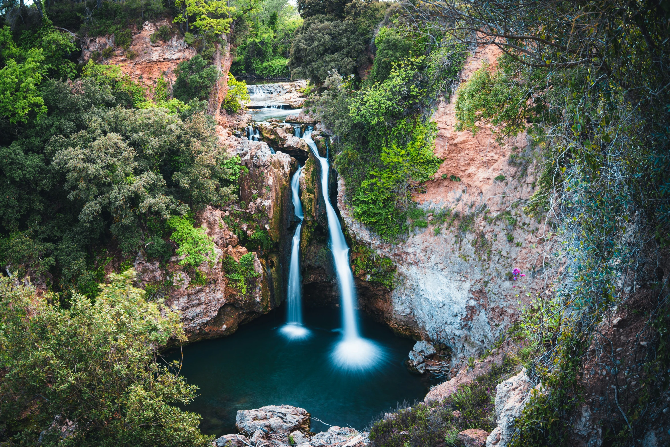 there is a blue pool below a waterfall