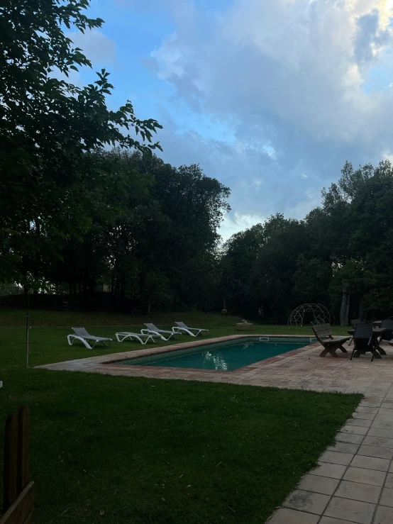 a large grassy area with pool and chairs