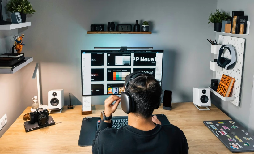 a person wearing headphones sitting at a desk with a monitor