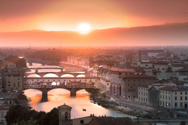 the sun setting over a river and bridge