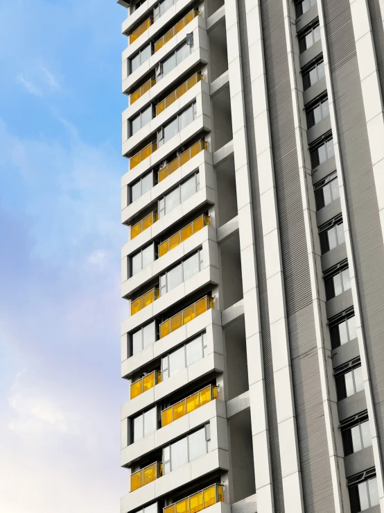 a very tall building with yellow windows against a blue sky