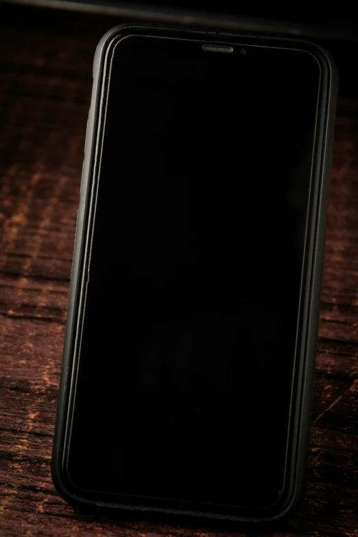 a black iphone sits on top of a wooden table