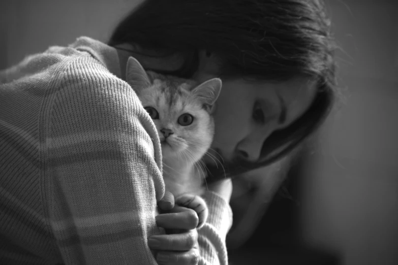 a girl holding a cat while covering her face with both hands