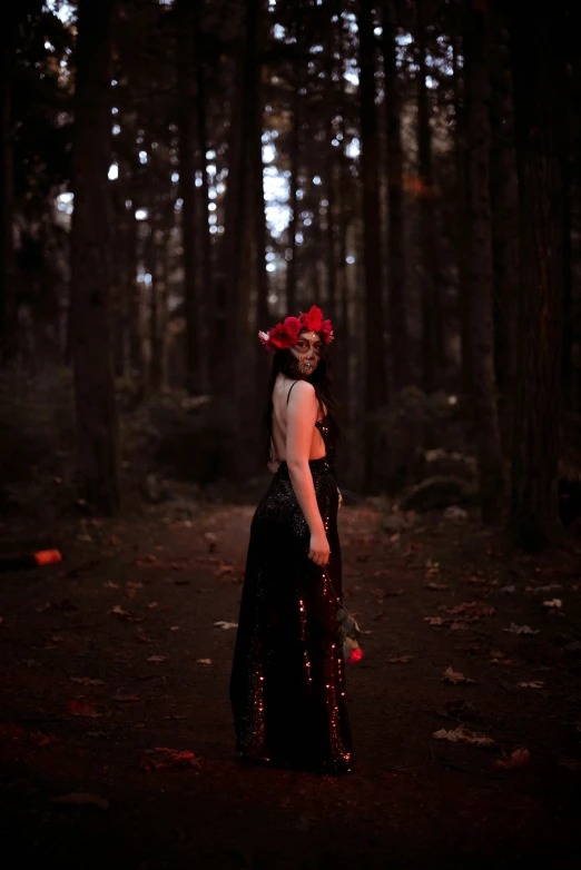 an old woman with a flower in her hair standing in the woods