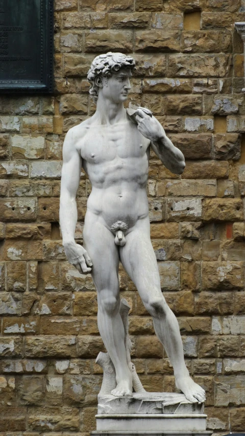 a statue of a man standing in front of a brick wall