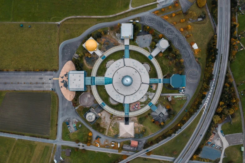 an aerial view of a circular building next to a highway