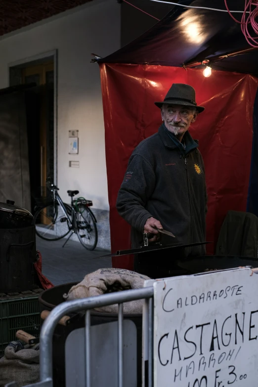 an old man standing in front of a cart and red flag