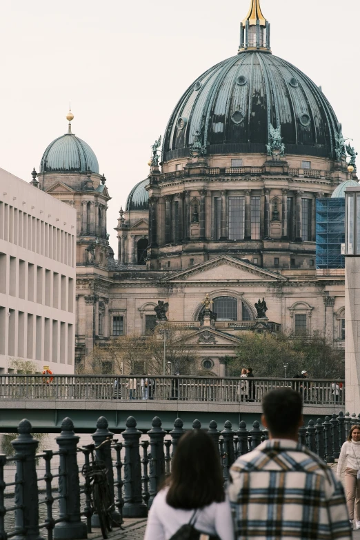 people walking across a bridge looking at a large building