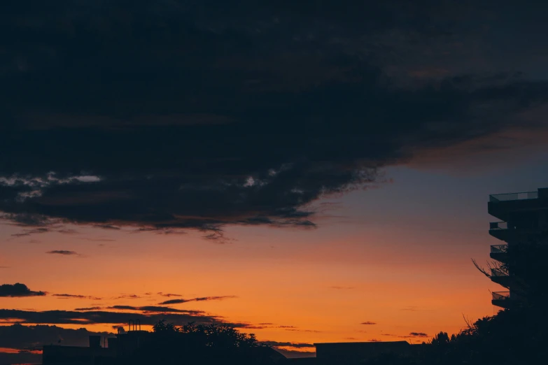 a tall building is silhouetted by the clouds in this cityscape